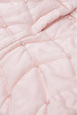 Close-up of a pink quilted fabric with pearl-like embellishments