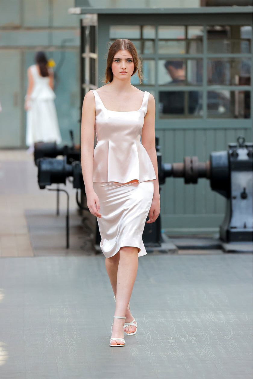 Woman in a white dress walking on a runway with industrial background