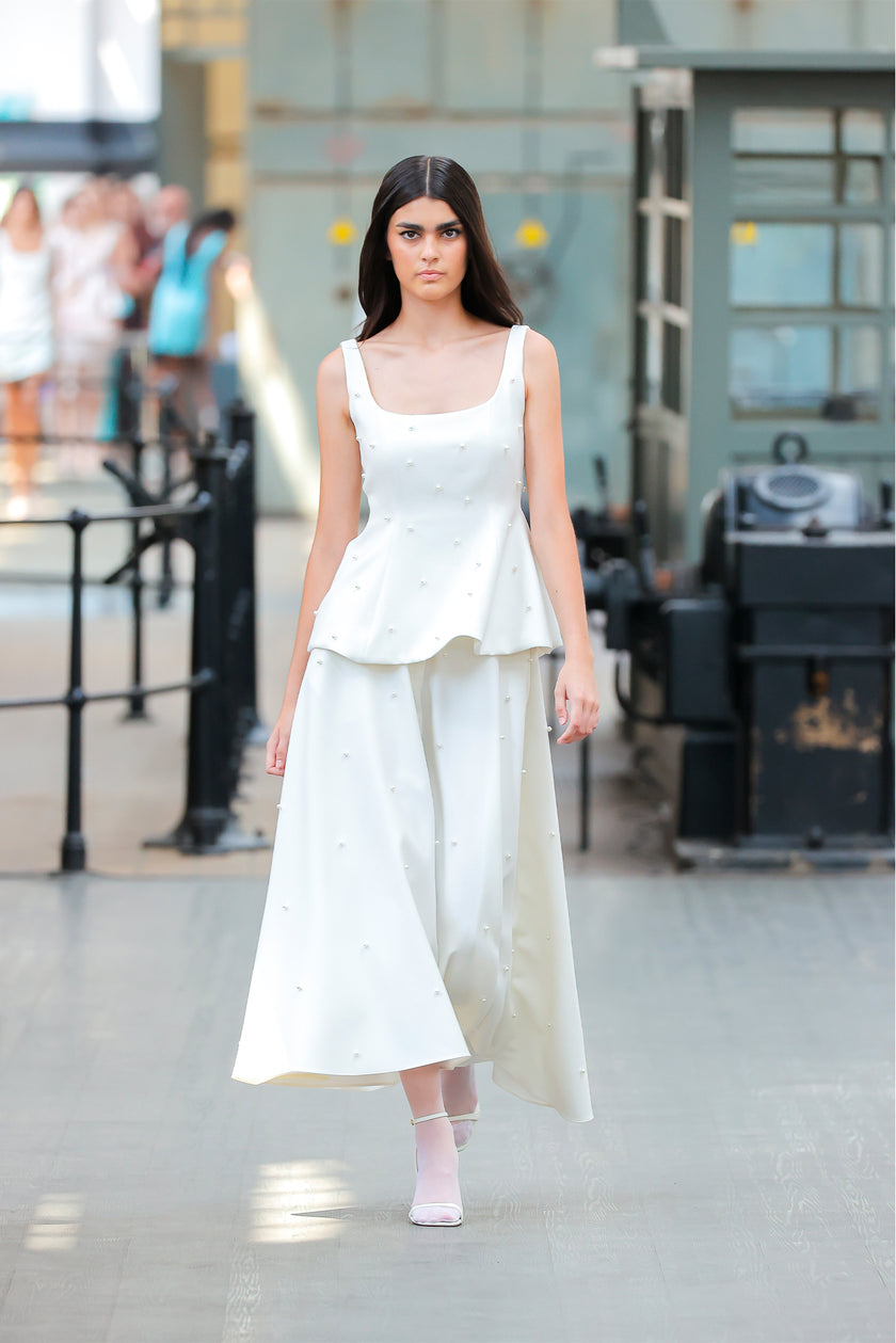 Woman wearing a white dress in an indoor setting with blurred background