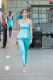 Woman in a turquoise outfit walking on a runway with blurred background