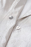 Close-up of a light gray fabric with two silver buttons.