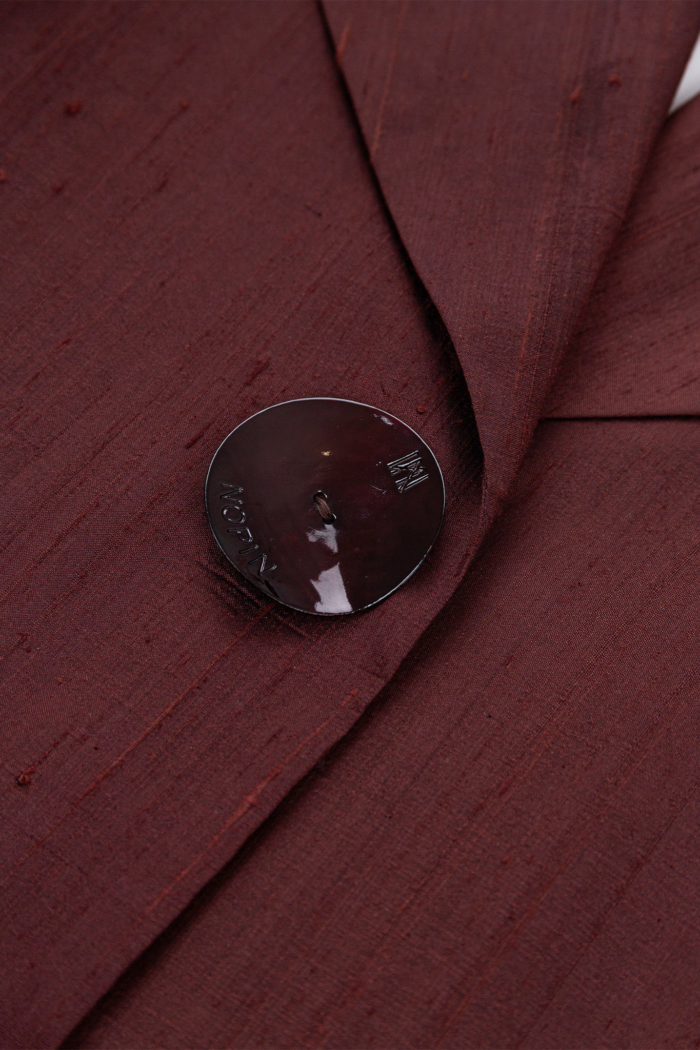 Close-up of a button on a burgundy fabric