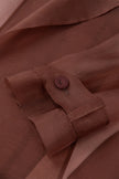 Close-up of a brown shirt with a button on a matching fabric background