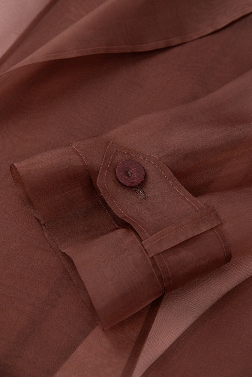 Close-up of a brown shirt with a button on a matching fabric background