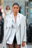 Woman wearing a light gray trench coat on a blurred street background