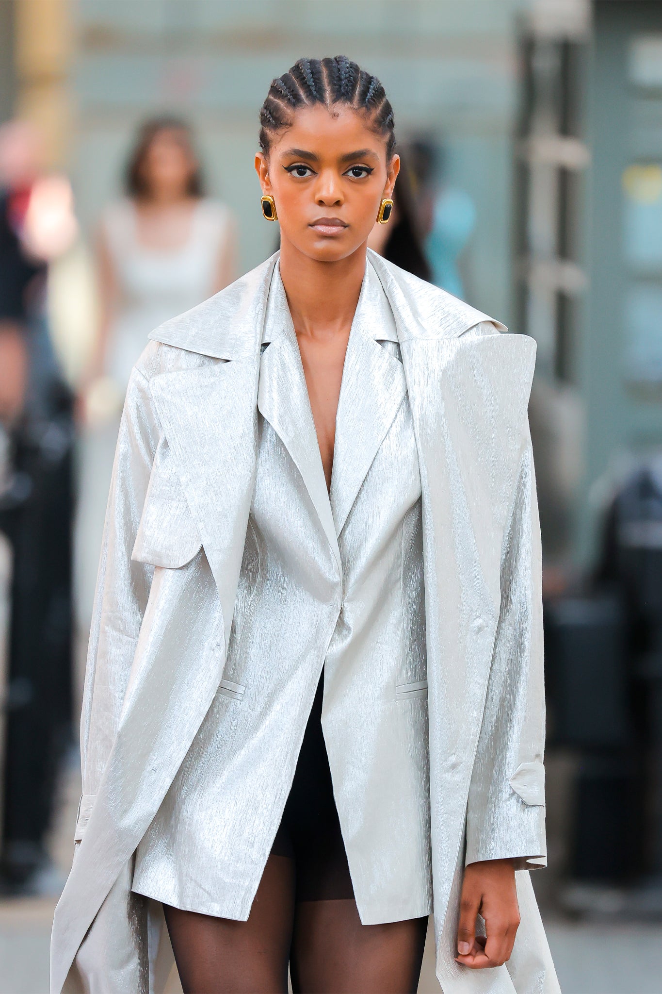 Woman wearing a light gray trench coat on a blurred street background
