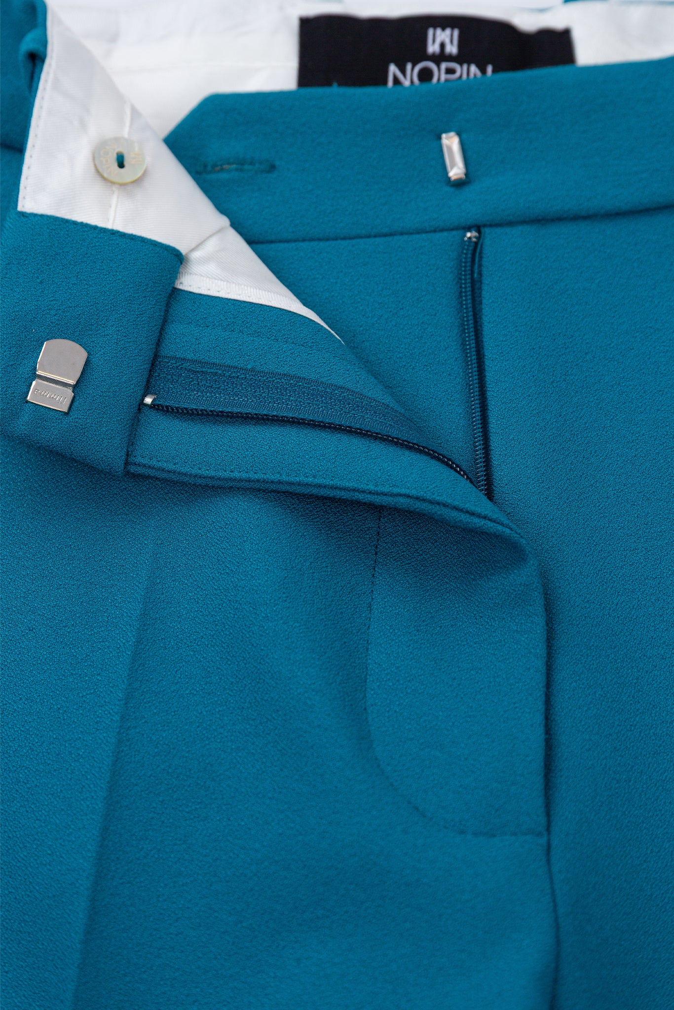 Close-up of a blue suit with white shirt and visible brand name on cufflinks.