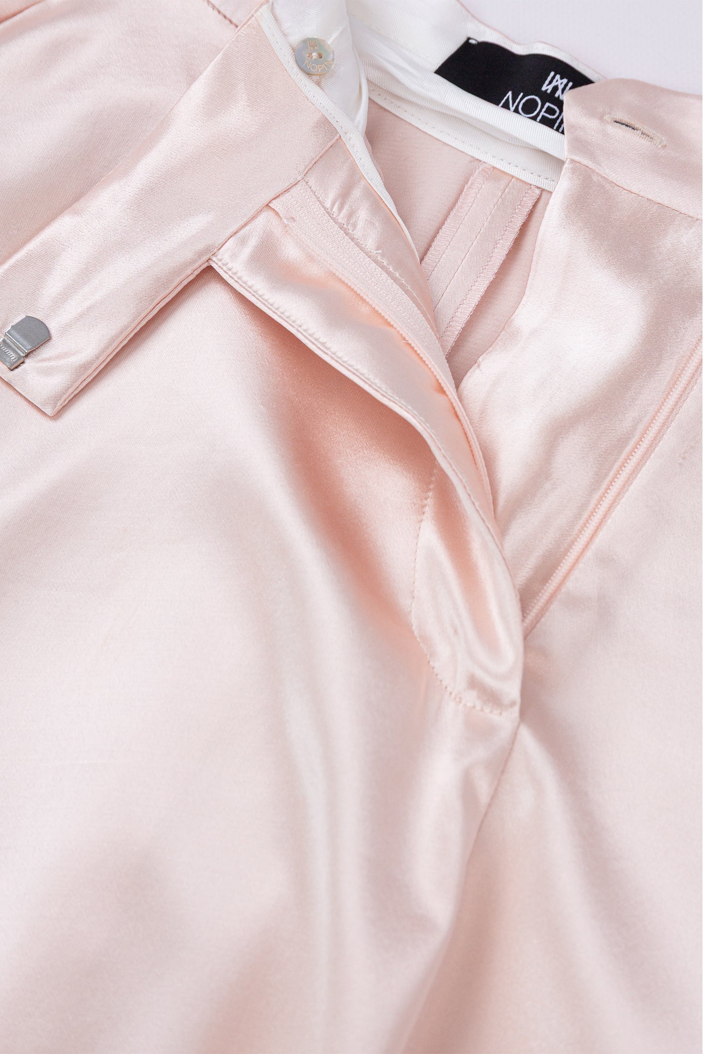 Close-up of a light pink jacket with a brand label on a white background