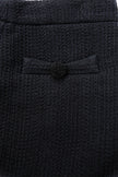 Close-up of a textured black fabric with a button detail