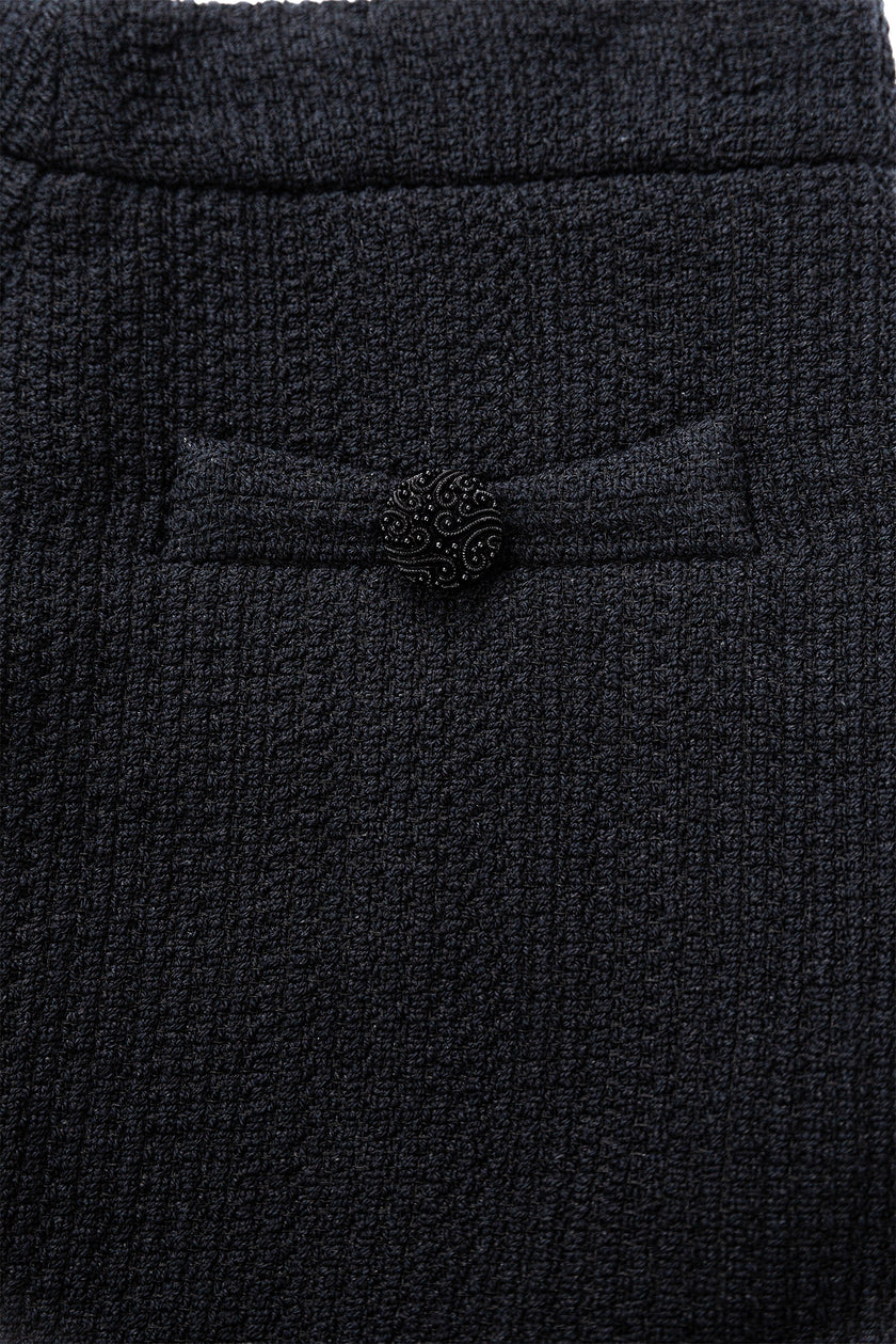 Close-up of a textured black fabric with a button detail