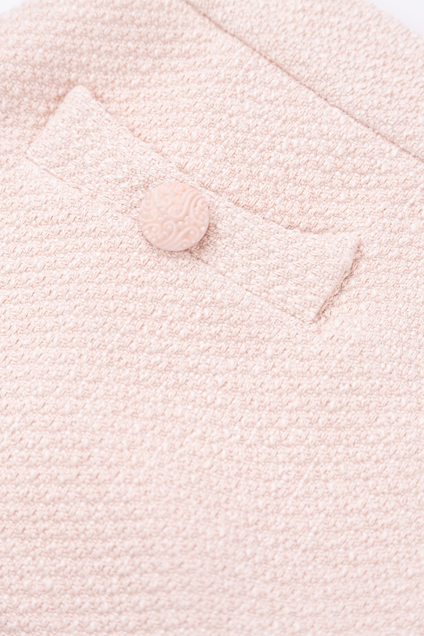 Close-up of a textured pink fabric with a button