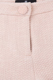 Close-up of a pink textured fabric with a button and brand label.
