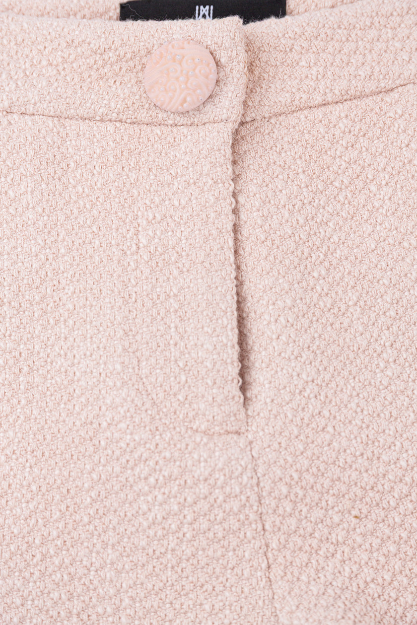 Close-up of a pink textured fabric with a button and brand label.