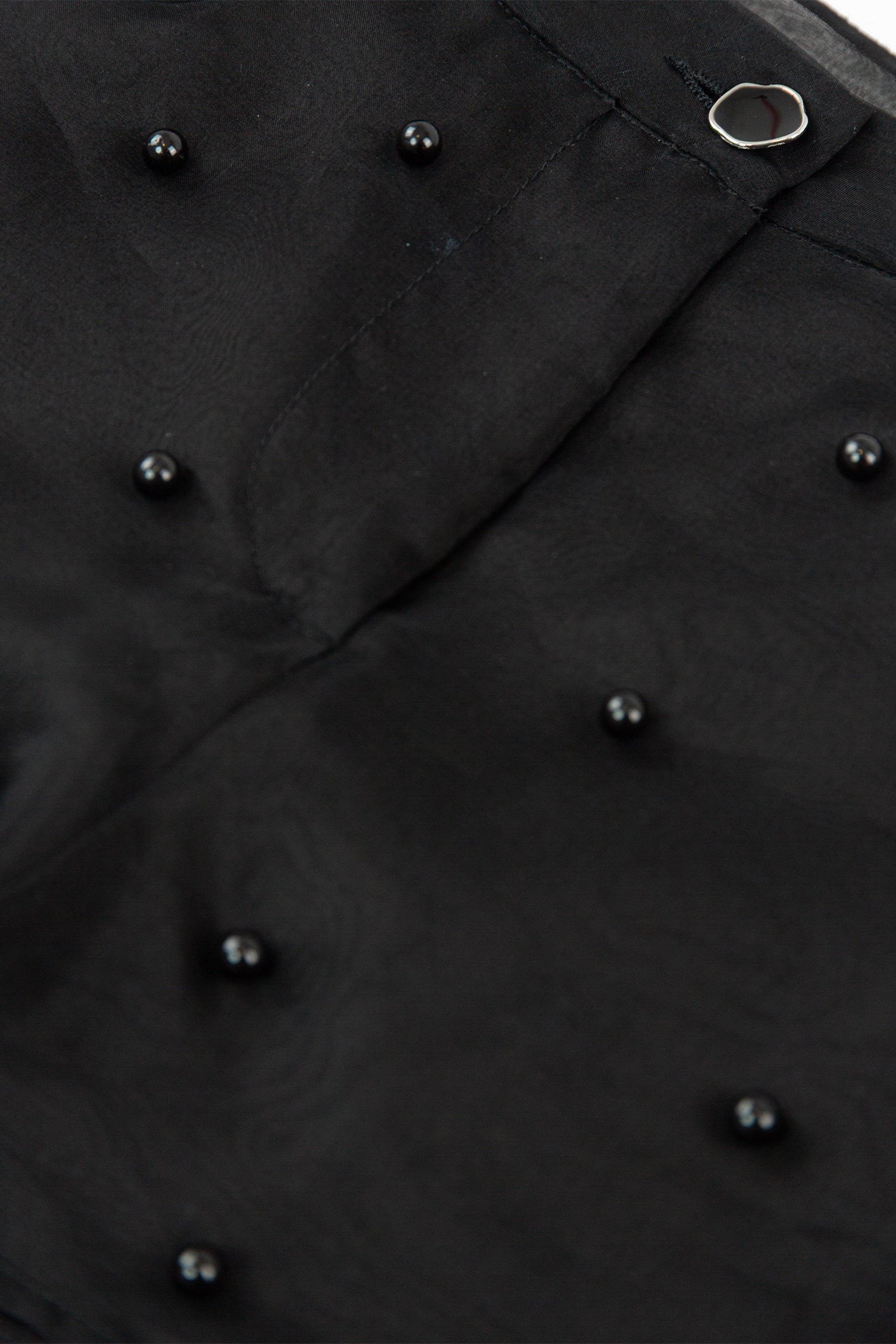 Close-up of a black coat with buttons on a plain background