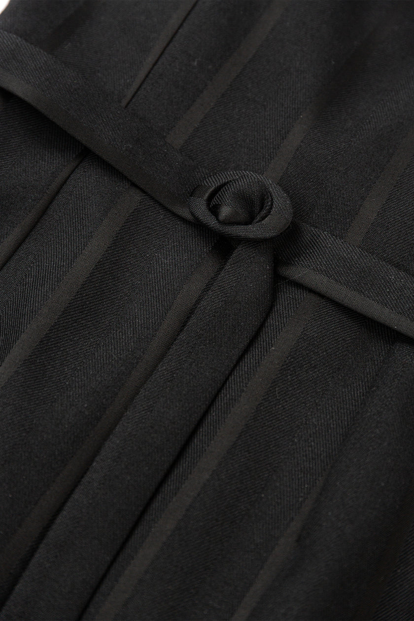Close-up of a black coat with a button detail