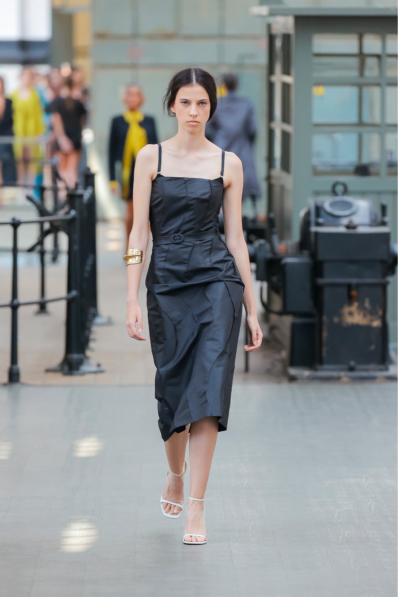 Woman in a black dress walking on a city street with blurred background