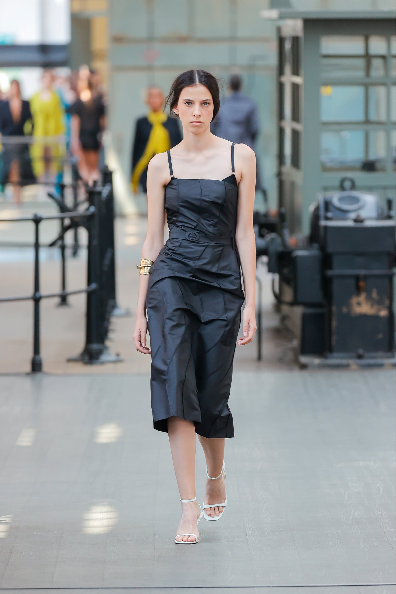 Model wearing a black outfit on a runway with blurred background