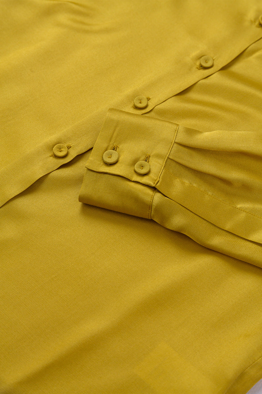 Close-up of a mustard yellow shirt with buttons and a pocket.