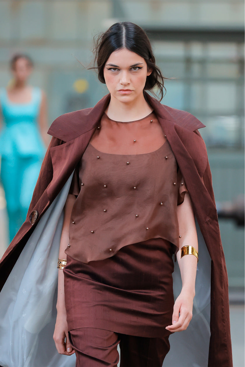 Woman wearing a brown outfit with a coat in an urban setting