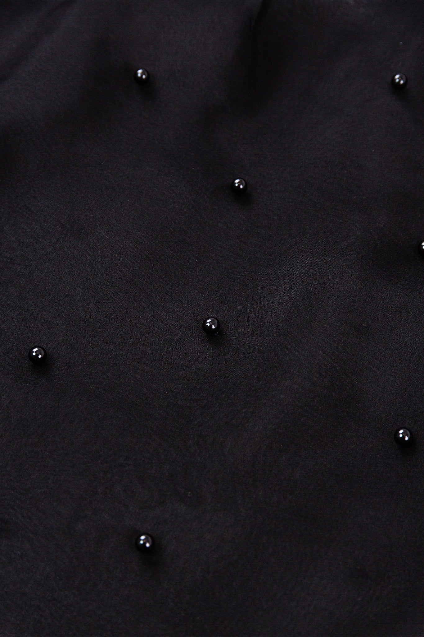 Close-up of a textured black surface with small black beads.