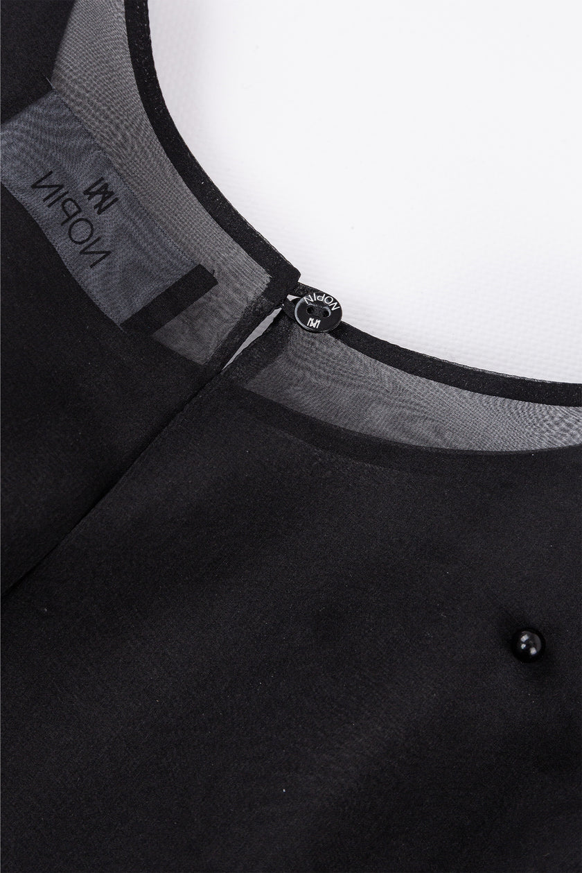 Close-up of a black garment with a zipper and visible brand logo on a white background