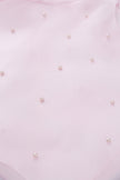 Close-up of a light pink fabric with small pearl-like embellishments.