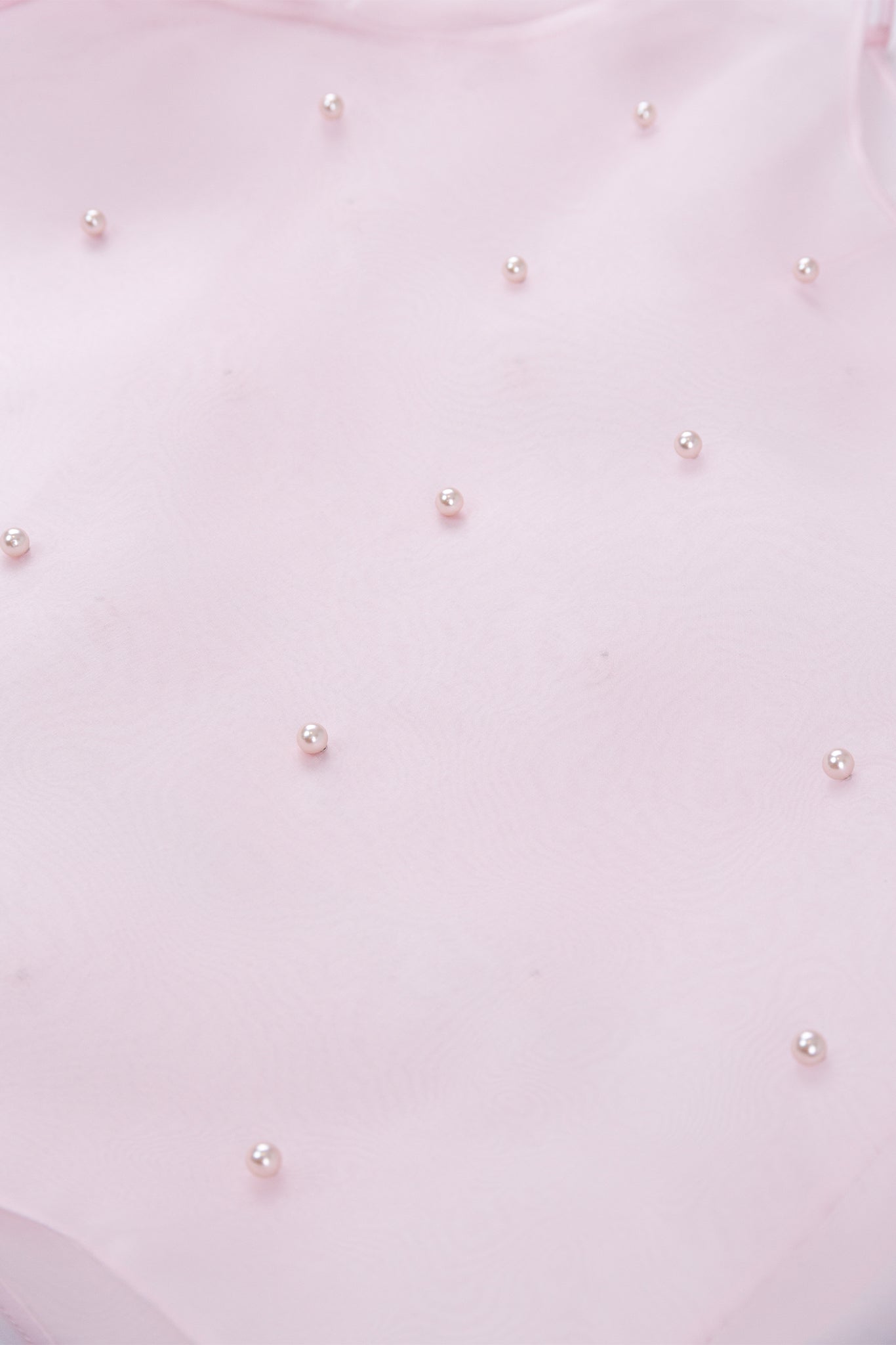 Close-up of a light pink fabric with small pearl-like embellishments.