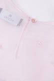 Close-up of a light pink shirt with a button and label detail.