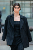 Woman wearing a black coat over a black dress in an urban setting