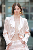 Woman wearing a light pink satin outfit with a blurred background