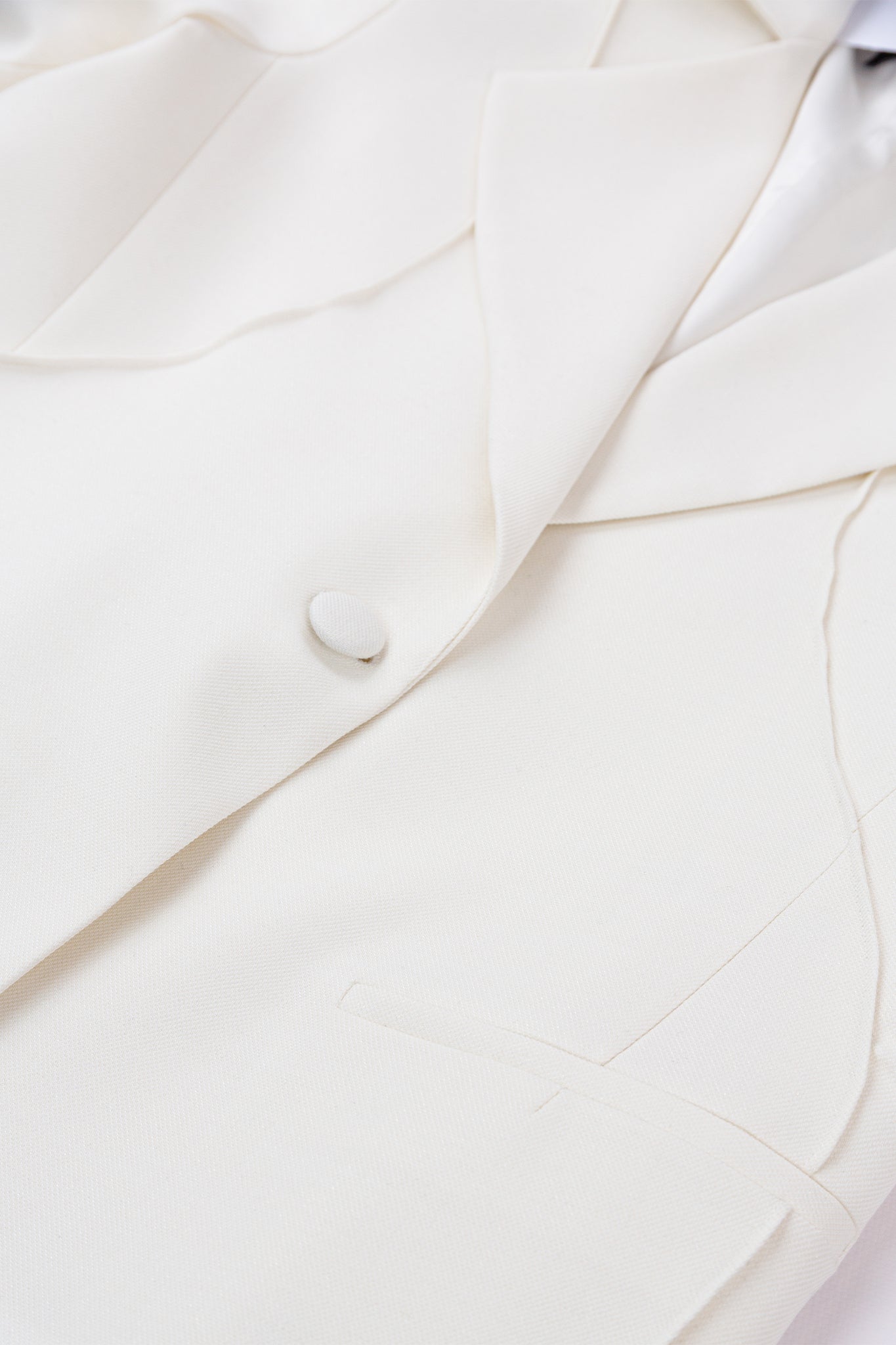 Close-up of a white suit jacket with a button