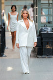 Woman in a white suit walking on a street with blurred background