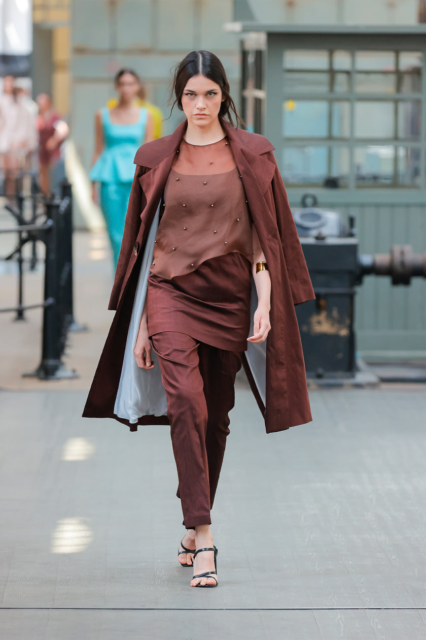 Woman in a brown outfit walking outdoors with blurred background