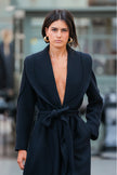 Woman wearing a black coat with a deep neckline in an urban setting