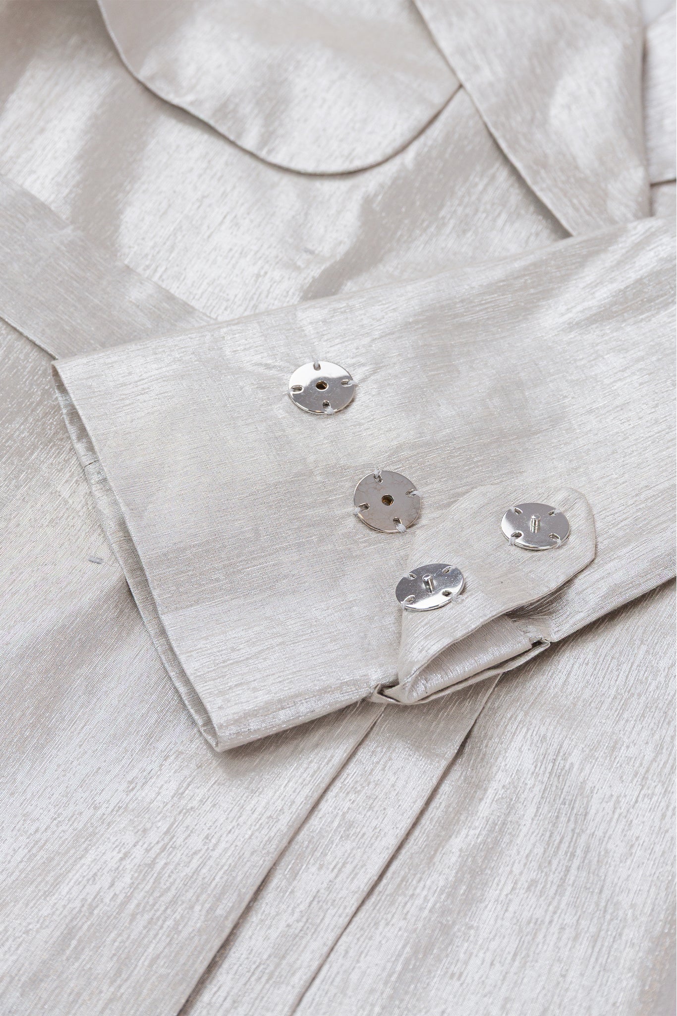 Close-up of a light gray shirt with buttons and collar details.