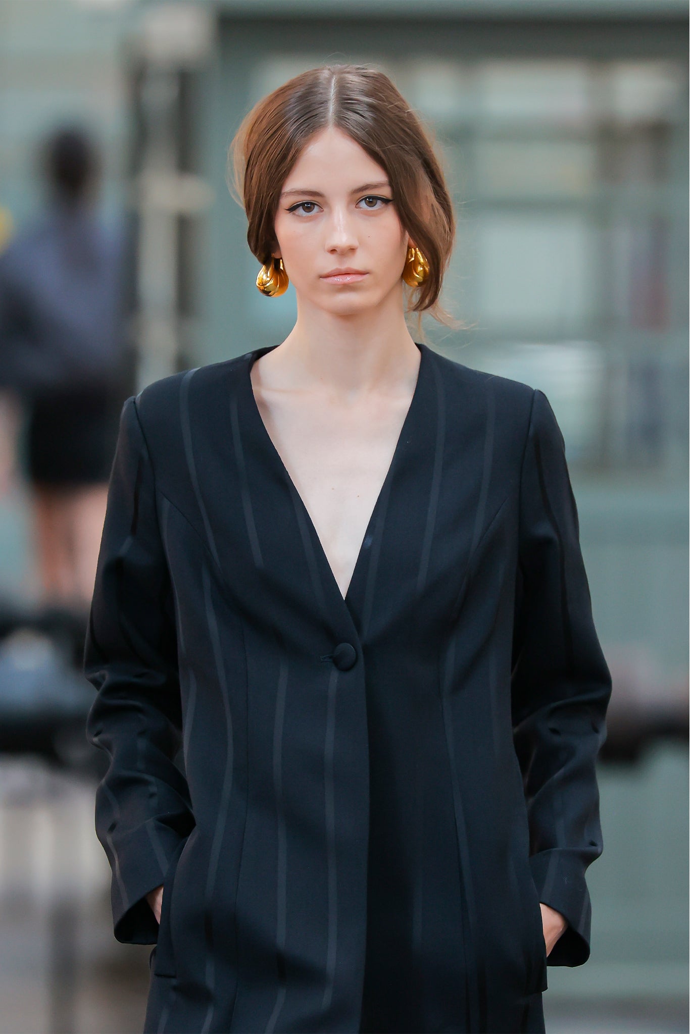 Woman wearing a black blazer over a beige top with a blurred background