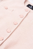Close-up of a pink textured fabric with buttons and a brand label.