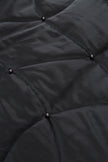 Close-up of a black quilted jacket with button details