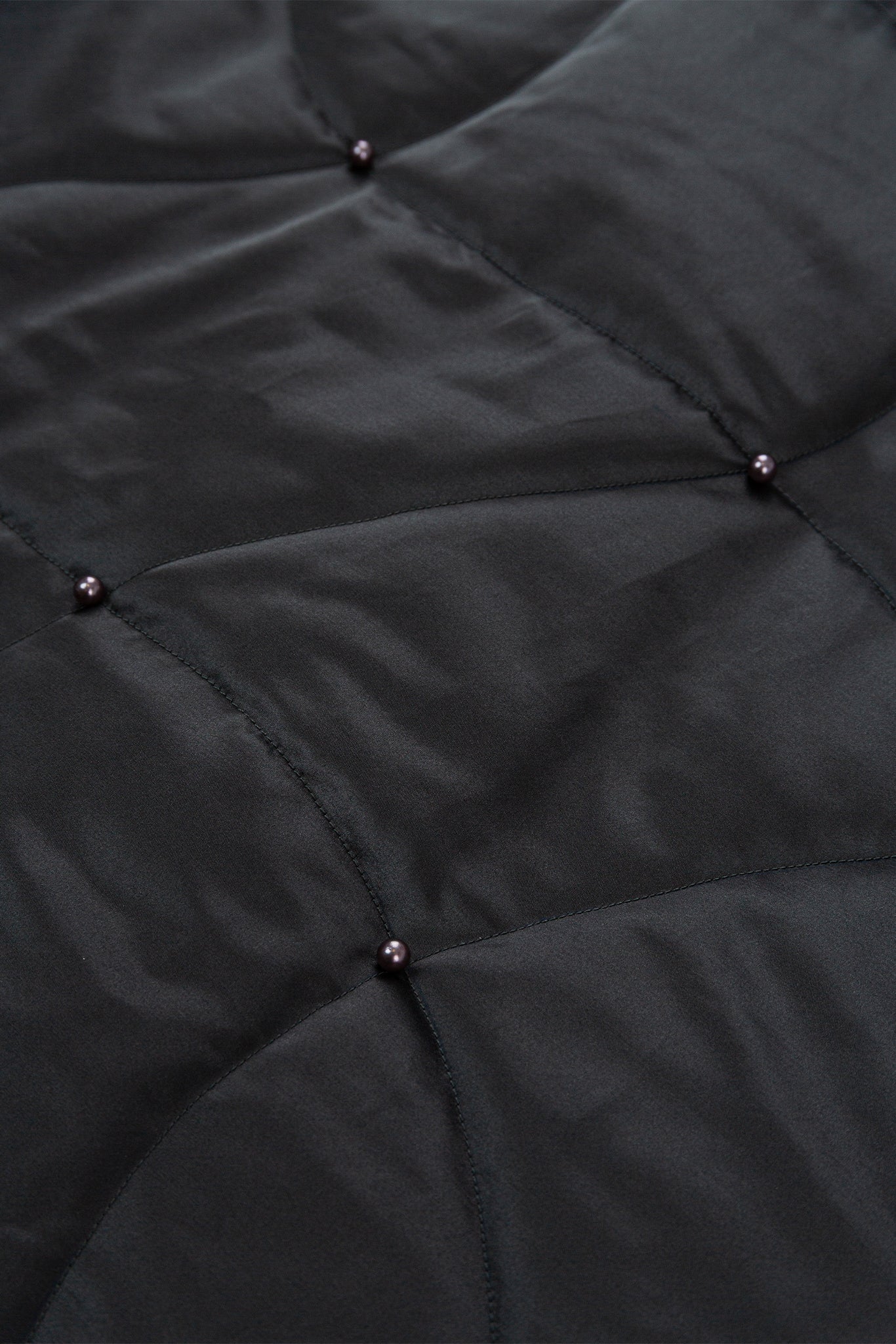 Close-up of a black quilted jacket with button details