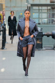 Model wearing a long puffer coat over a black outfit on a city street.