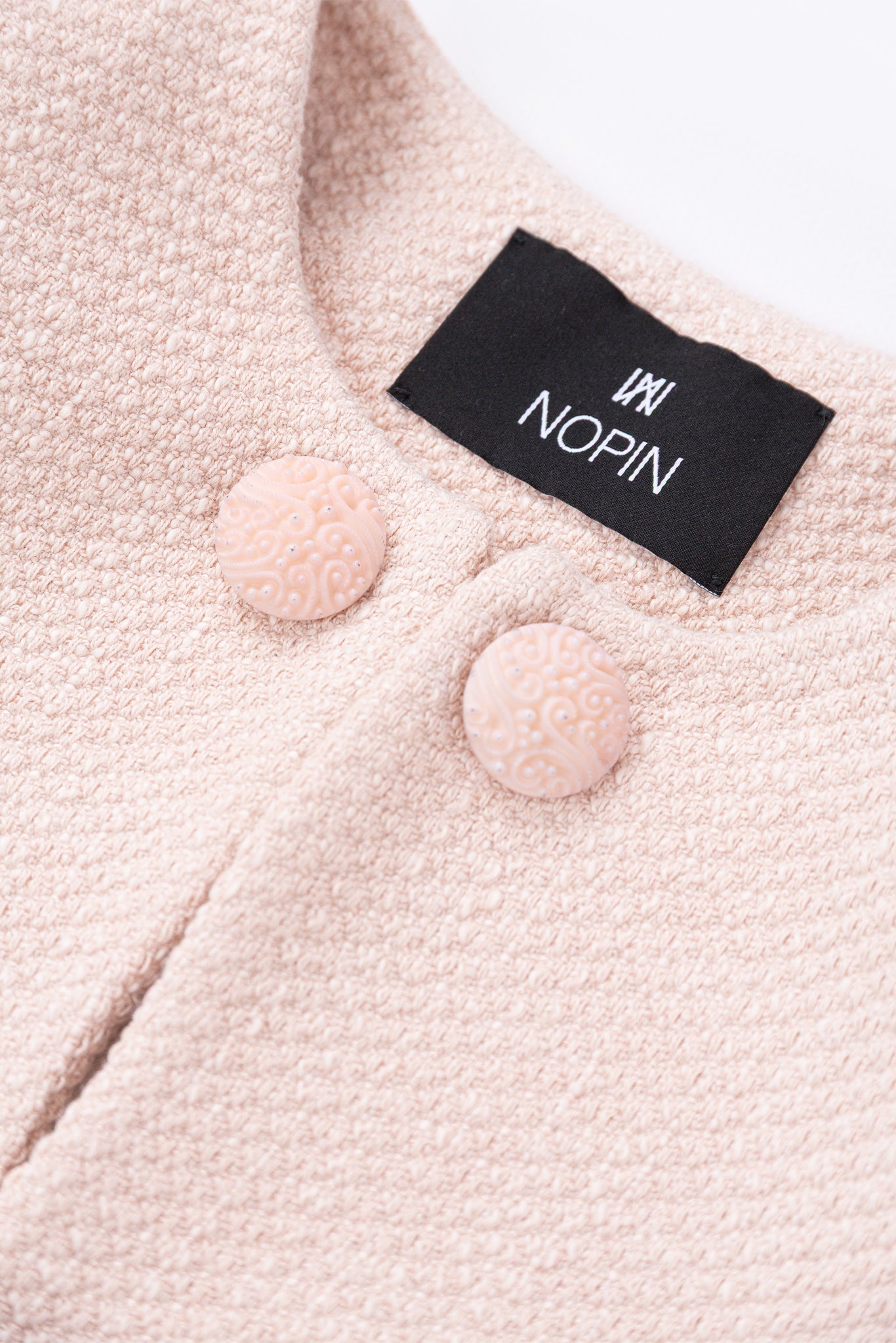Close-up of a pink textured garment with aNOPIN label.