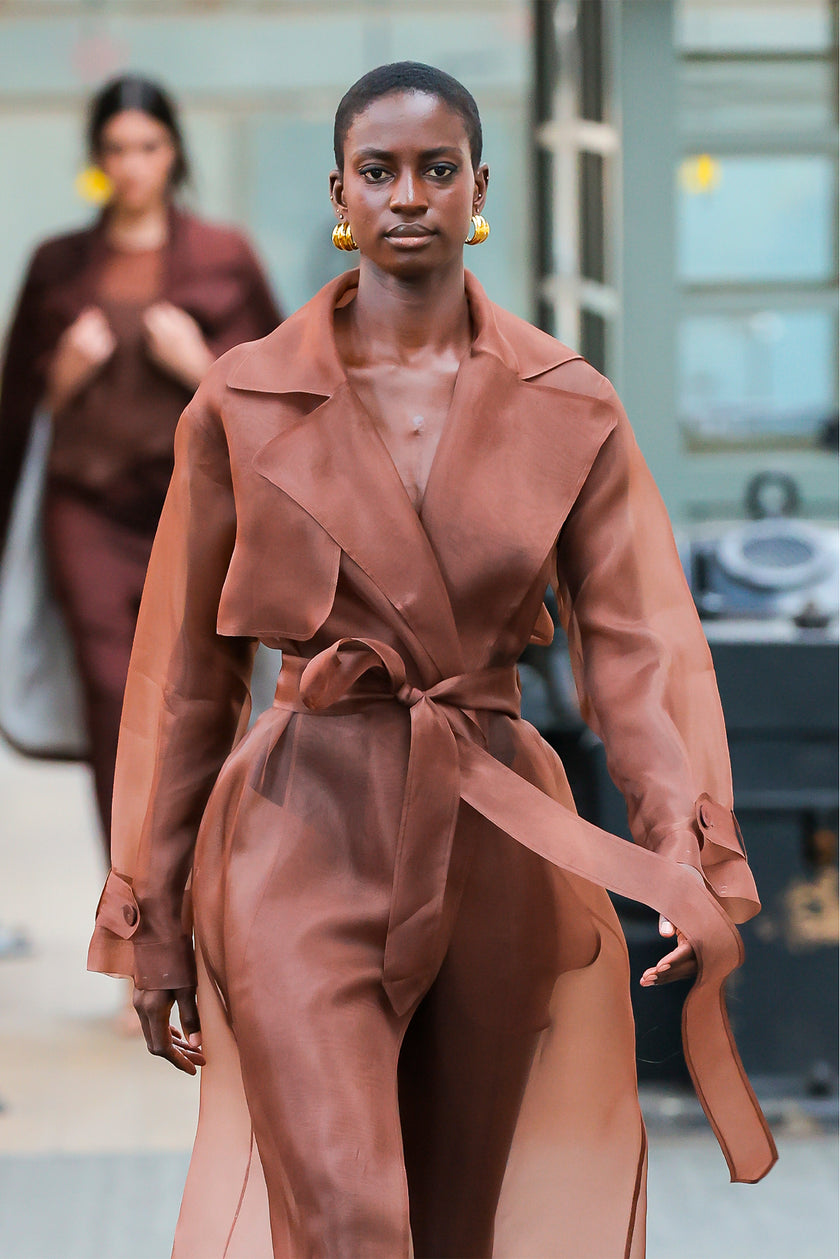 Woman wearing a brown trench coat with a blurred background